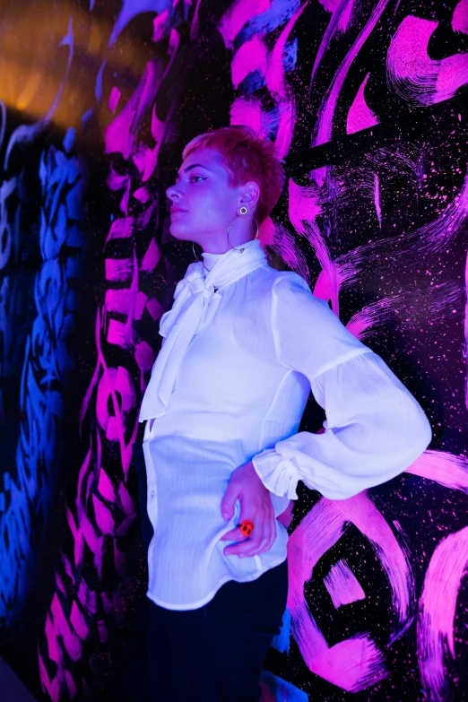 a man in white shirt standing against colorful wall