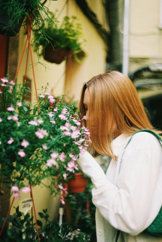 a woman holding onto a flower plant by a building