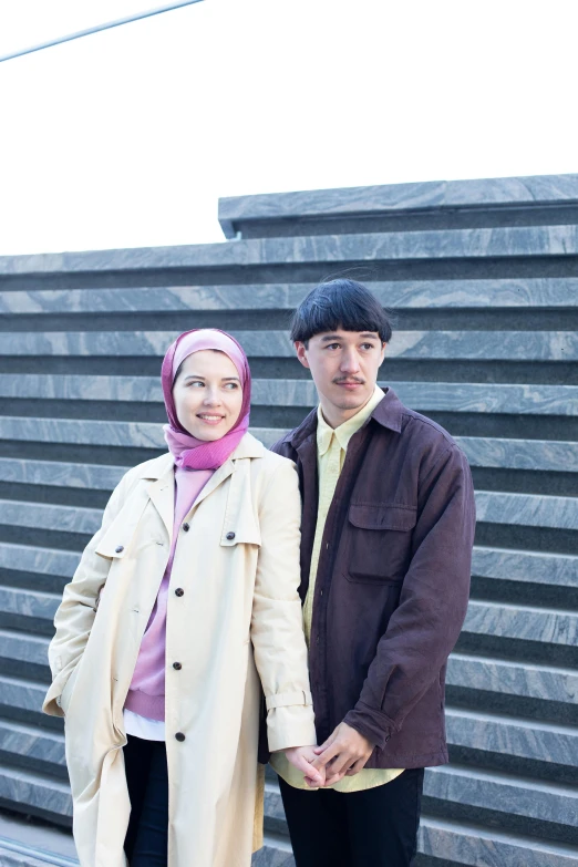 a couple standing next to each other in front of a building