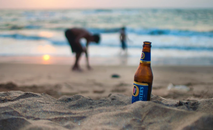 a bottle of beer laying on the beach