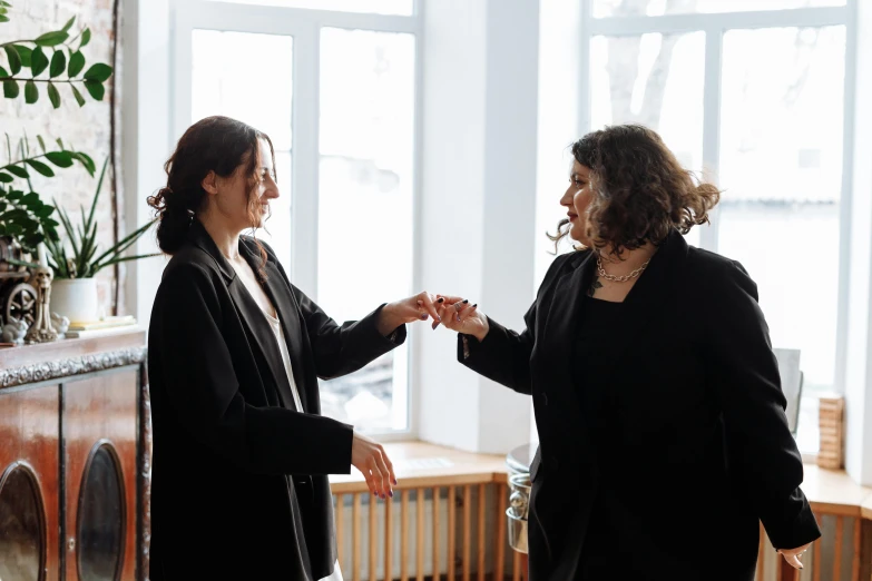 two woman hold hands in front of a fire place