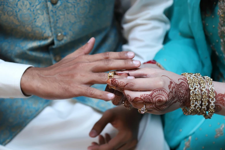 two brides exchanging a wedding ring with the groom in blue