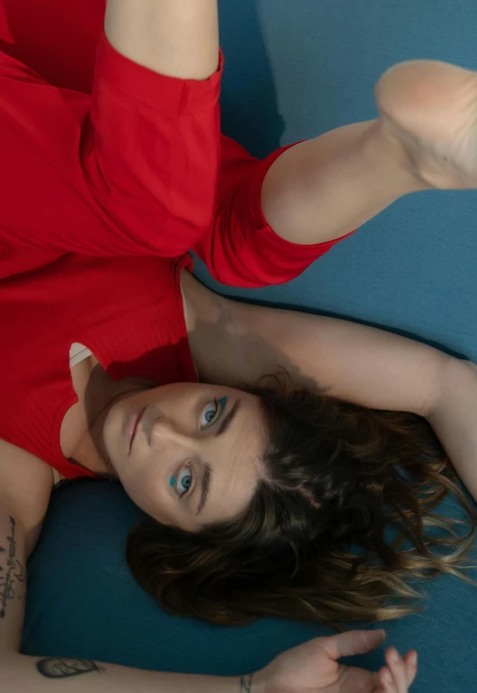 an attractive woman laying on a blue surface wearing red