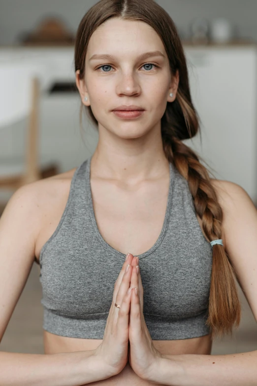 a woman is sitting in a yoga position with her hands folded