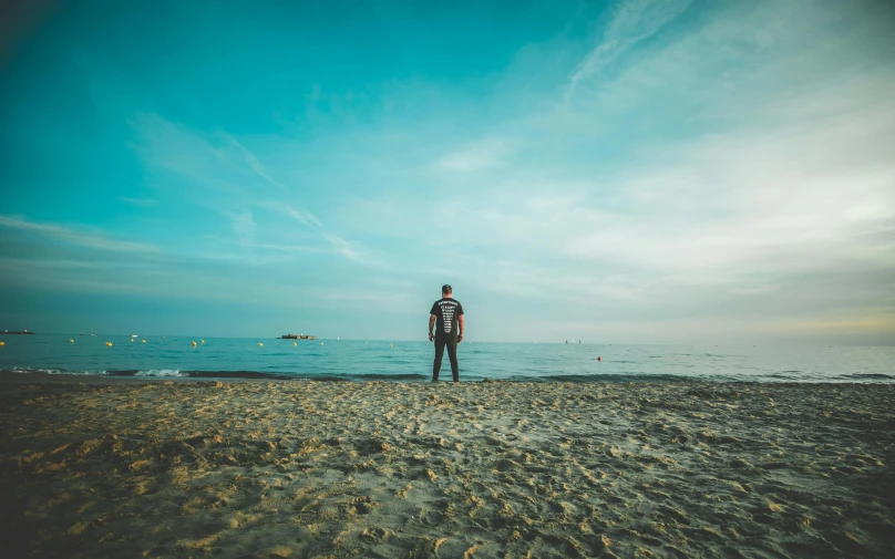 a man is standing on the beach next to the ocean