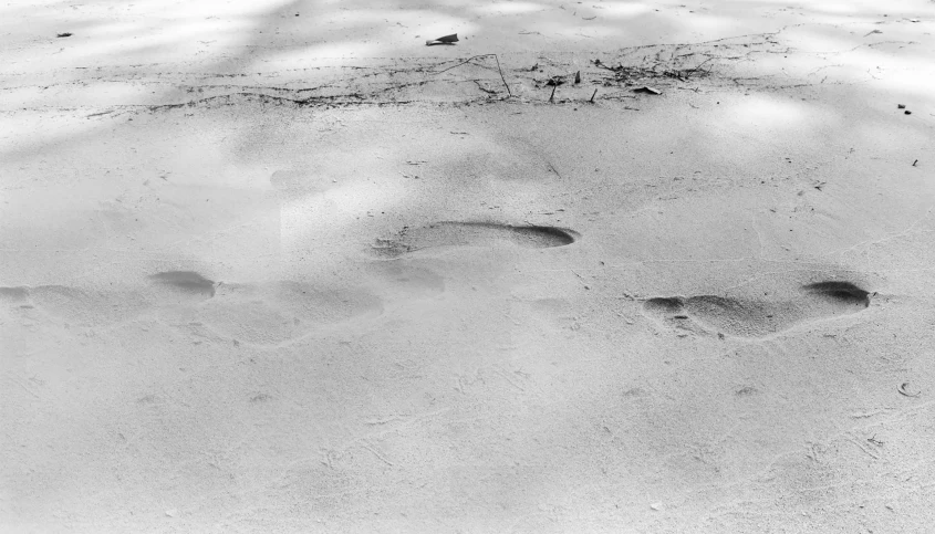 two footprints are shown in the sand with their backs turned