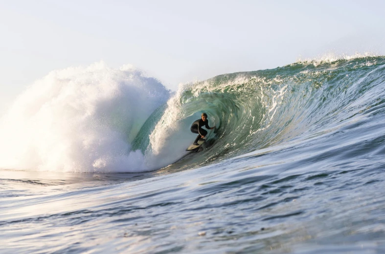 man in black wet suit riding on wave in ocean