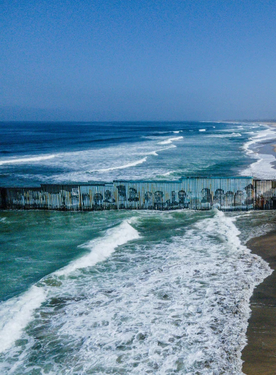 an ocean and shore line with a fence in the foreground