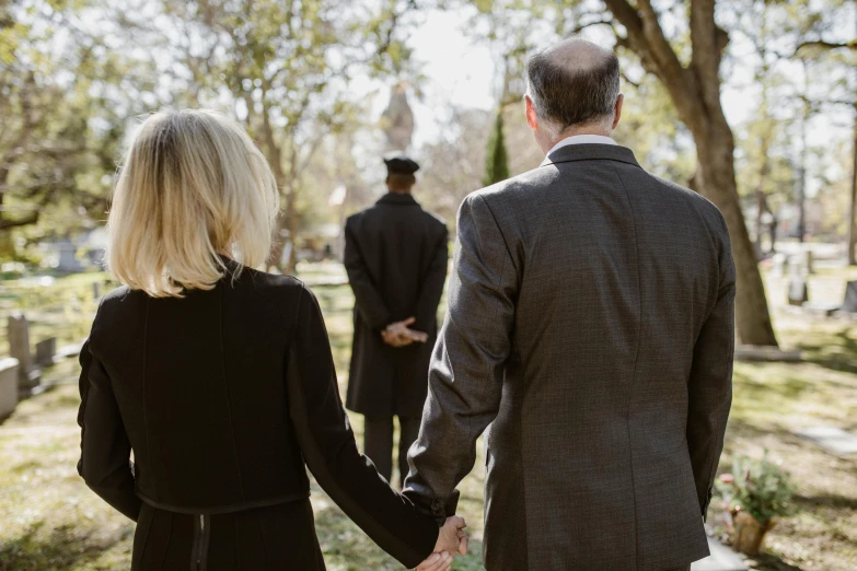 a couple holding hands in front of a cemetery