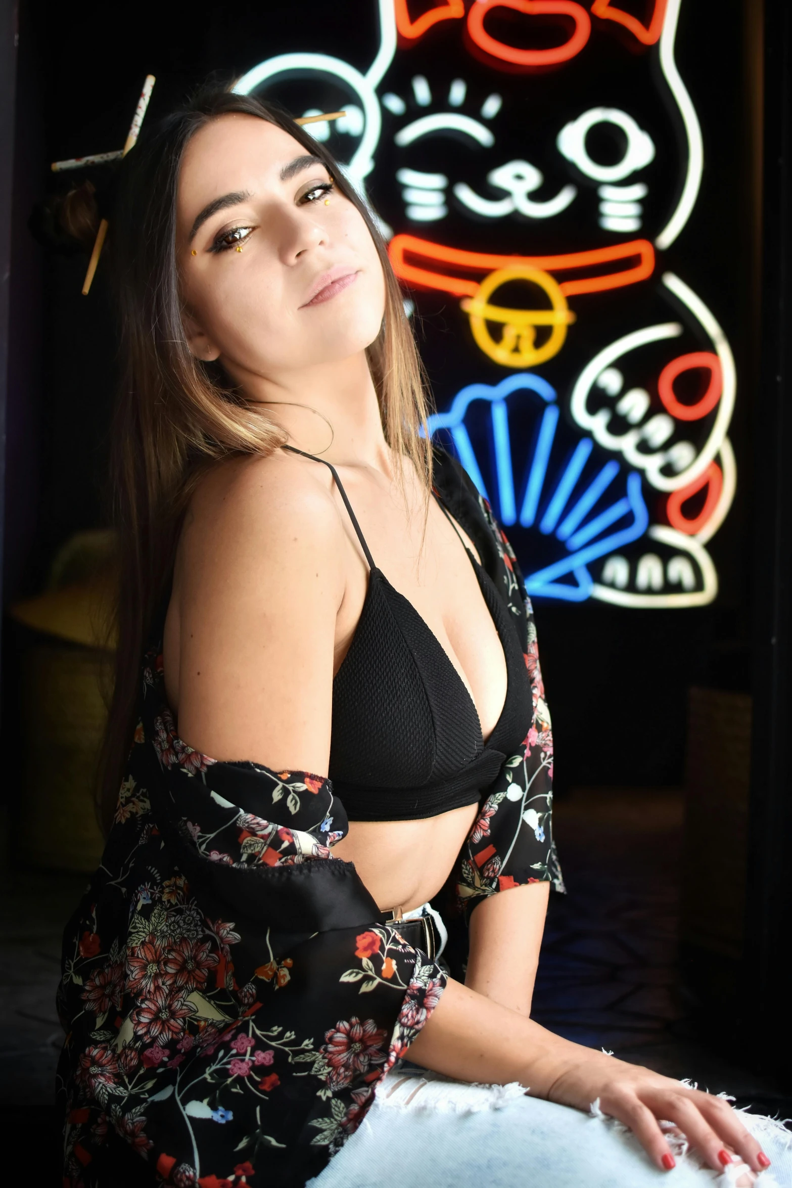 the young lady is posing in front of the neon sign