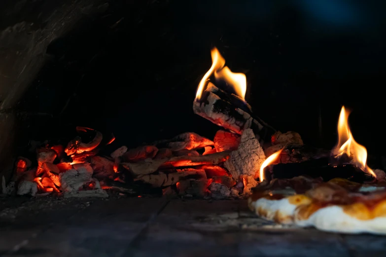 a pizza is sitting by an open fire in the oven