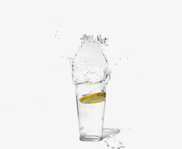 a splash of water in to a clear glass filled with a yellow piece of lemon