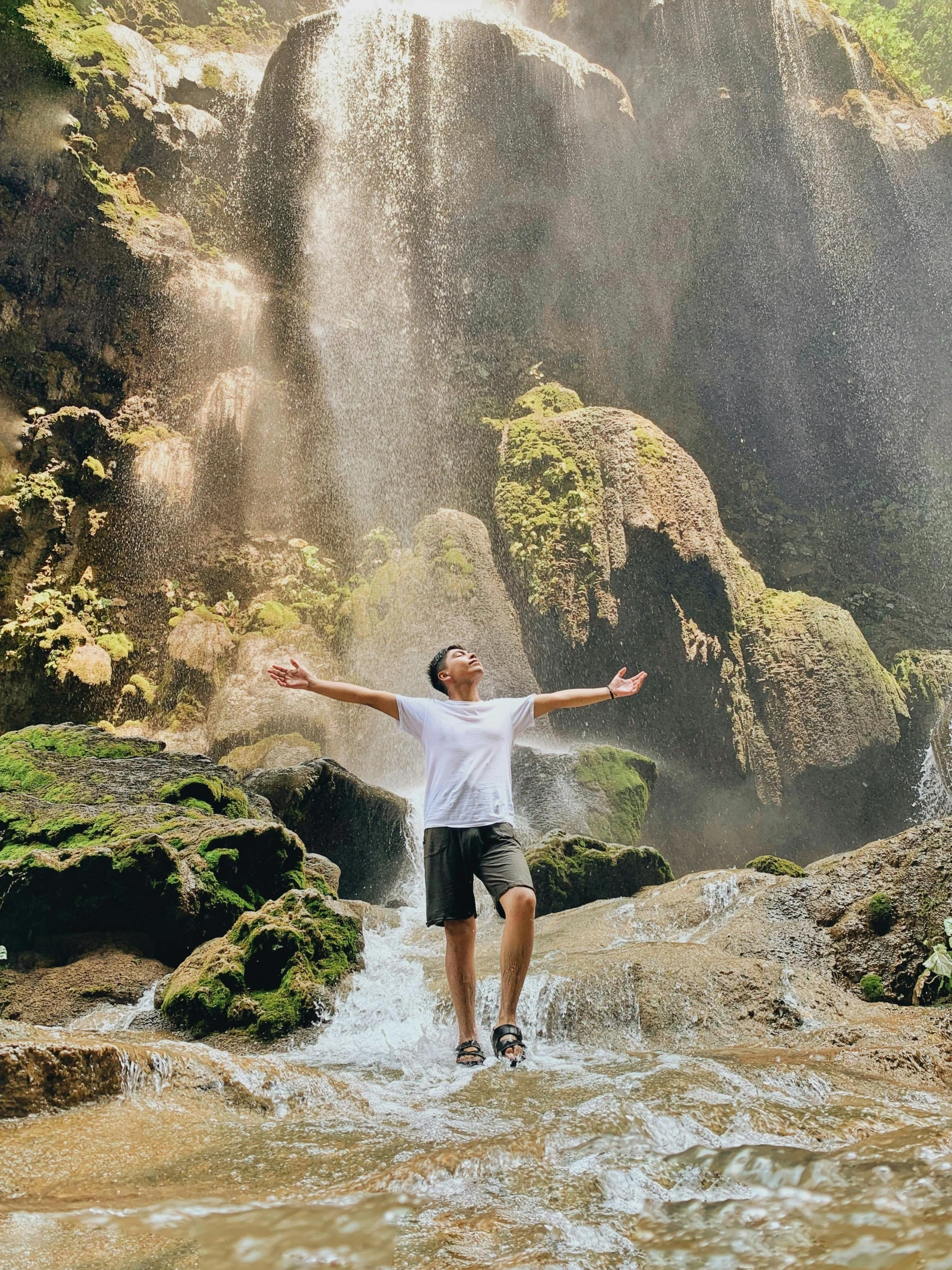 a man standing in front of a waterfall in a body of water