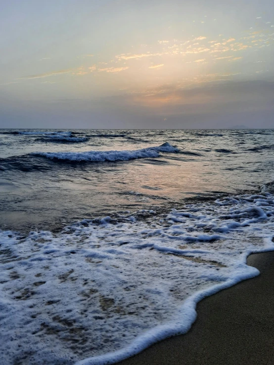 ocean waves crashing against a sandy shore