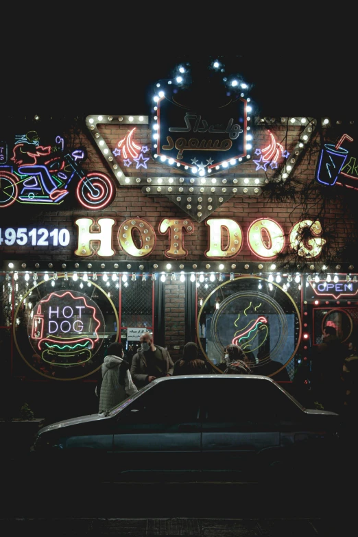 people gathered around the building with neon signs on it