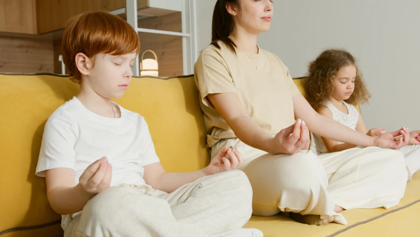 two young women and a man are sitting on a couch