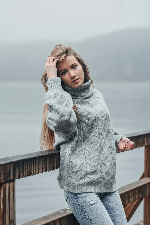 a woman posing for a portrait while leaning on the edge of a pier