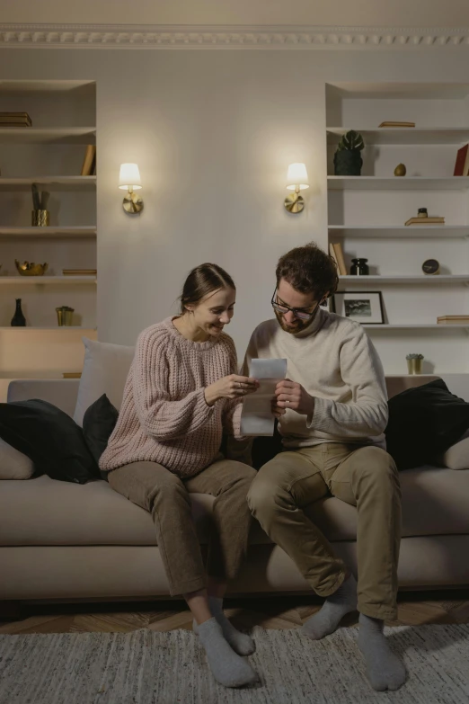 a man and woman are sitting on a couch looking at a tablet