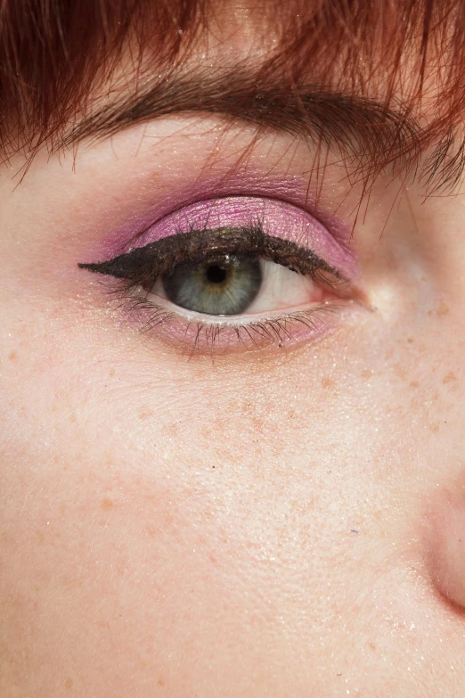 a close - up po of a women eye with pink, purple and black colored eyelashes