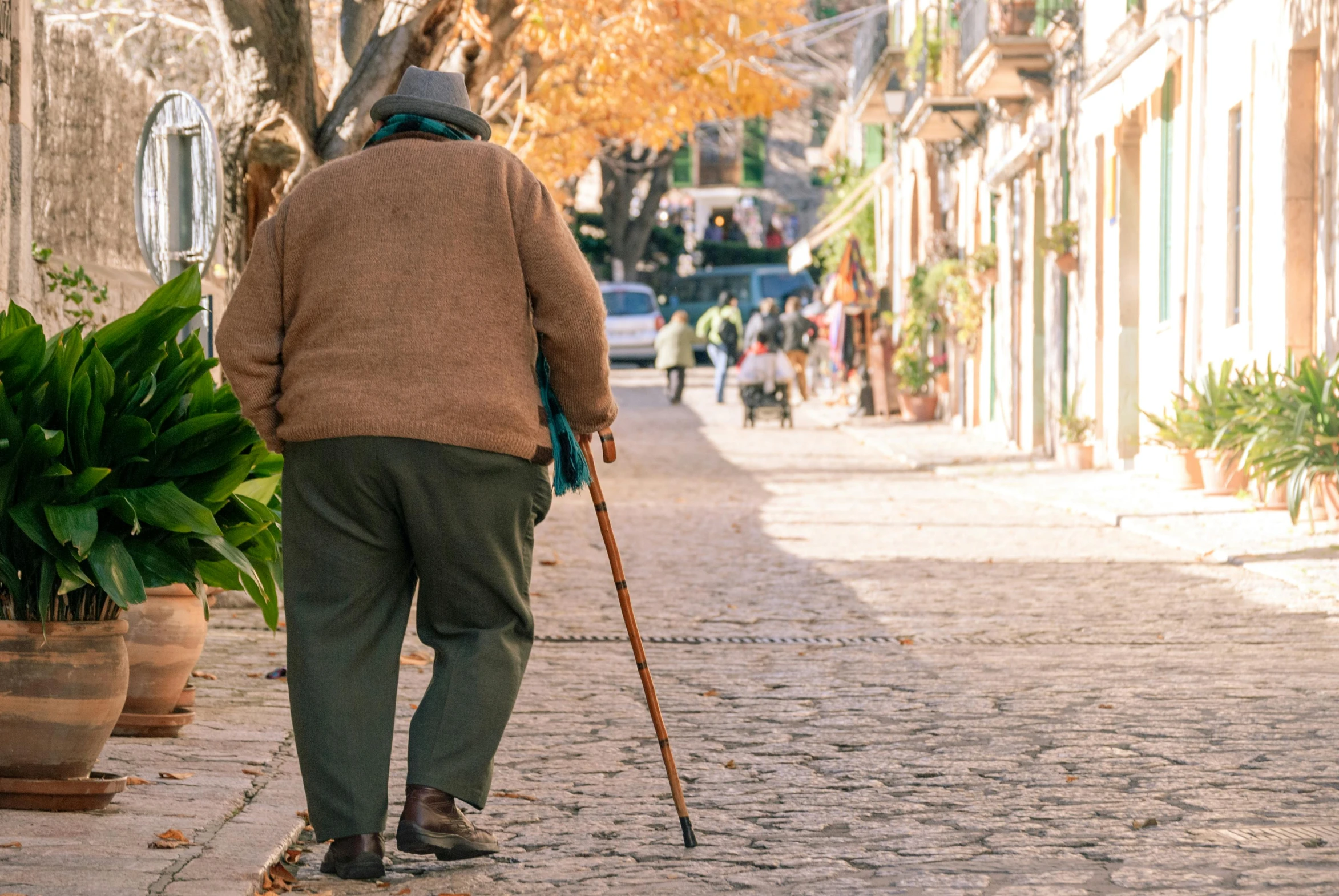 a man walks along a sidewalk in a courtyard while holding his cane