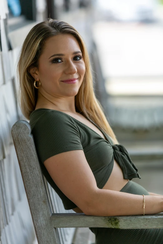 a woman sitting on a bench, posing for a po