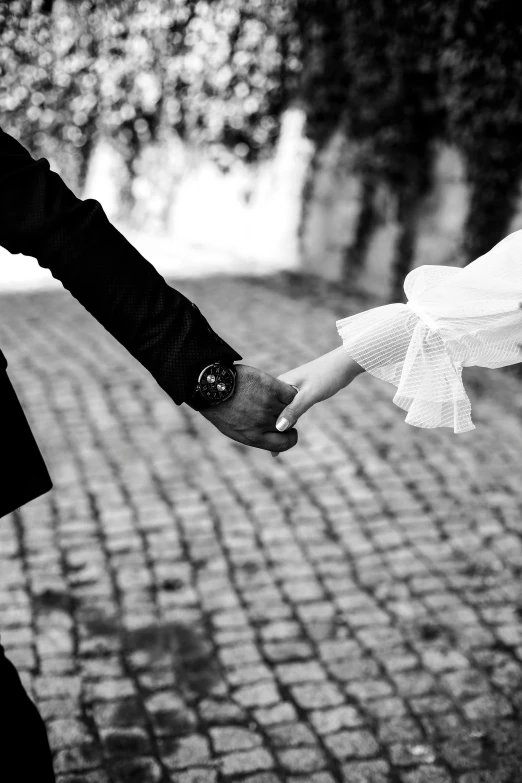 a black and white po of the bride and groom's hands, carrying each other