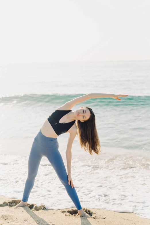 woman in yoga pose on the beach with a surf view