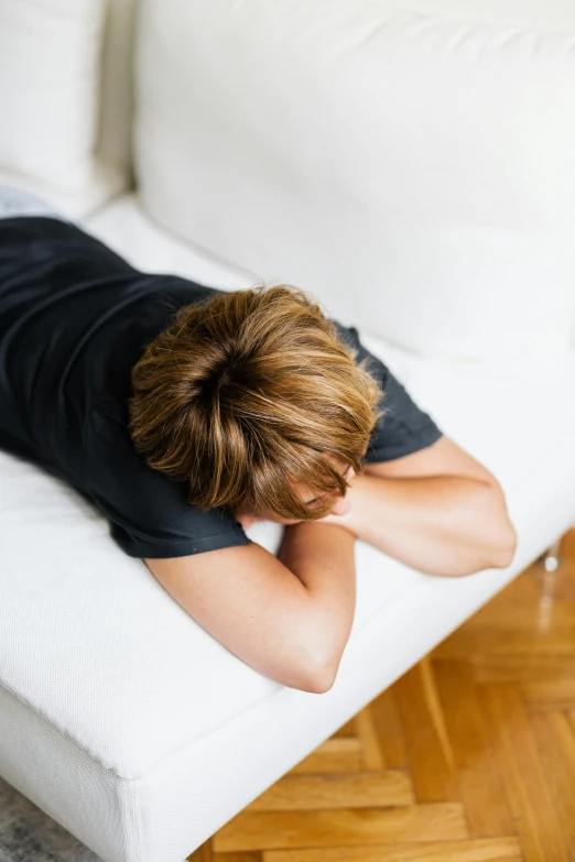 a boy laying on the top of a white couch