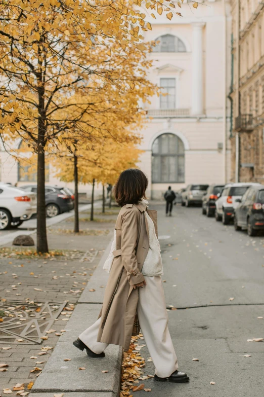 the woman is standing in front of a yellow tree