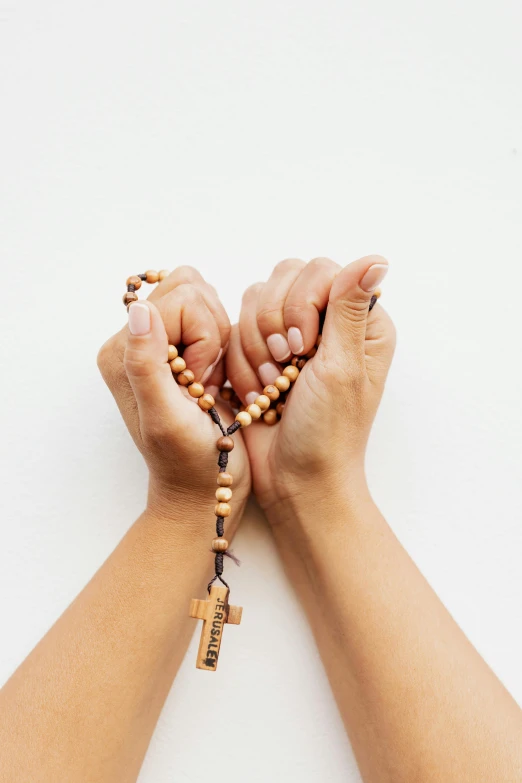 two hands holding a rosary with beads on it