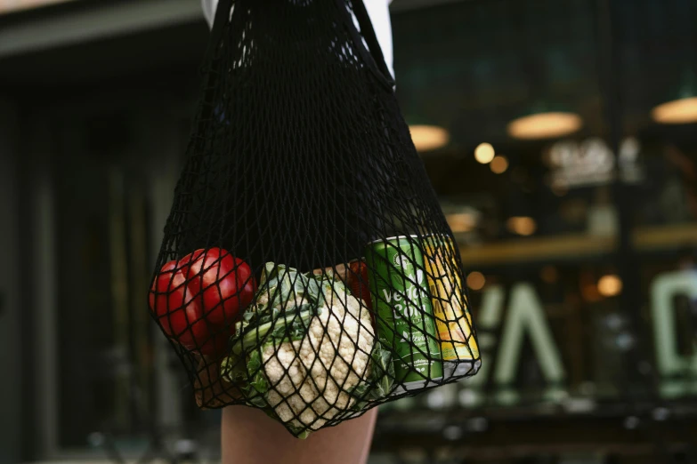 an unisex string bag has fruit and vegetables inside