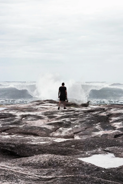 a person standing in front of the ocean watching waves crash