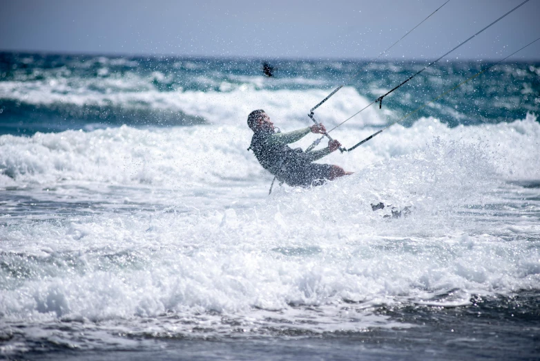 man in the ocean riding on the waves with a kite