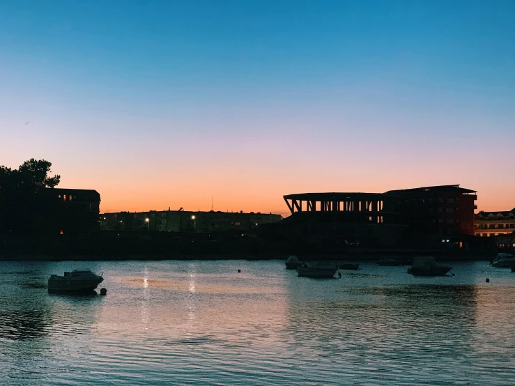 some boats are floating on the water at sunset