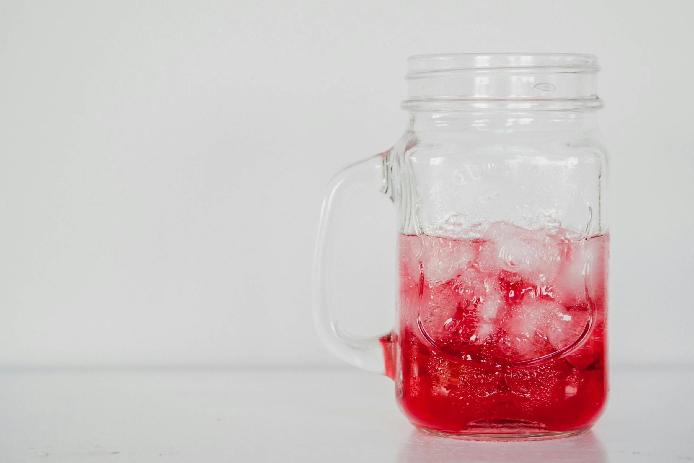 red liquid in a glass jar and a white background