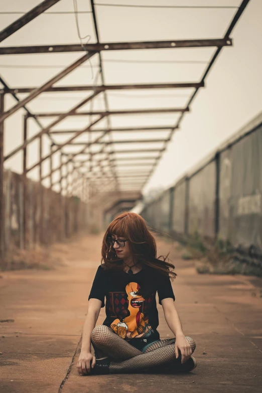 woman with a lion t - shirt sitting on the ground on her phone