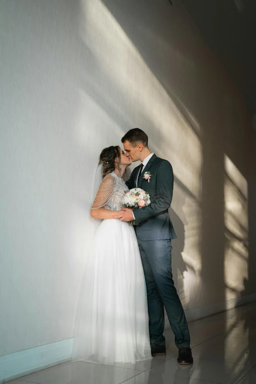 the newly married couple stands in the shadow against the wall