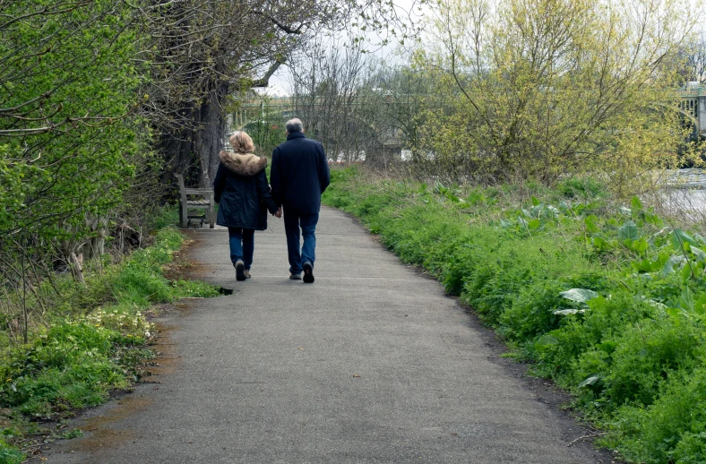 a couple is walking down a path holding hands