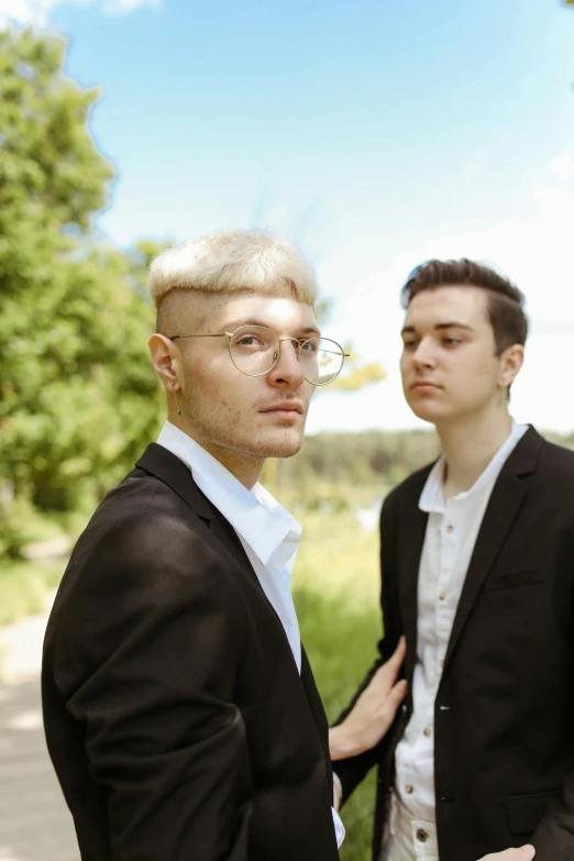 a boy in black jacket and another boy in white shirt and tie with light colored hair