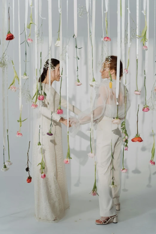 a couple in a studio holding hands under flowers