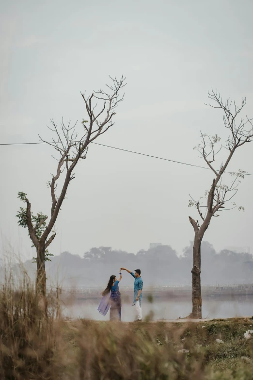 two people flying a kite next to trees