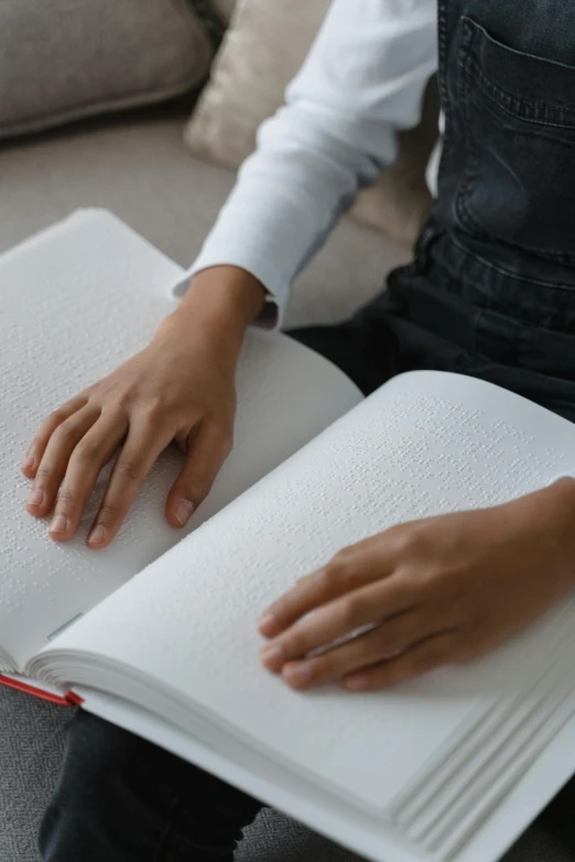 a person reading an open book on a couch