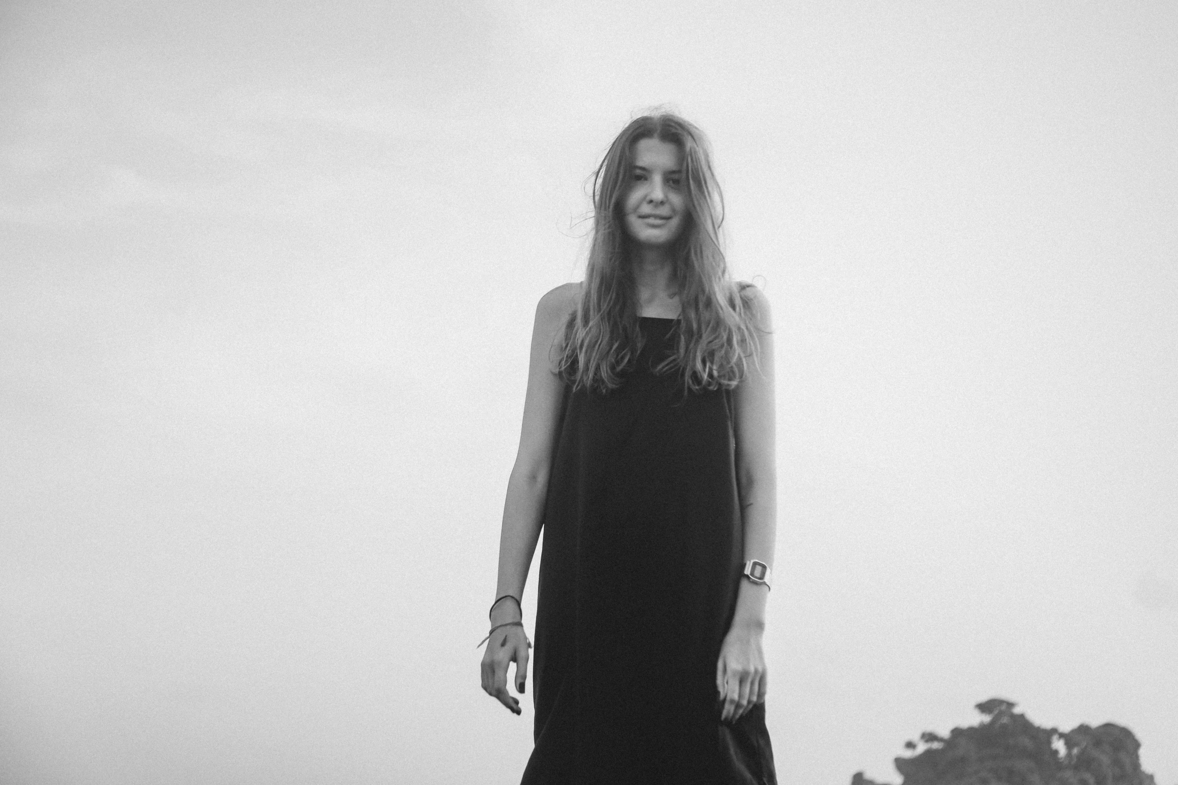 a young woman is wearing a black dress and is standing in a foggy field