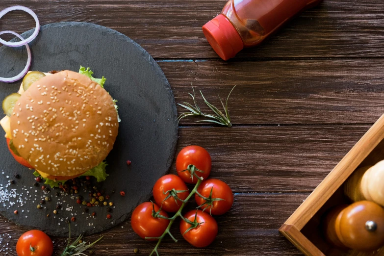 some tomatoes are next to a burger on a plate