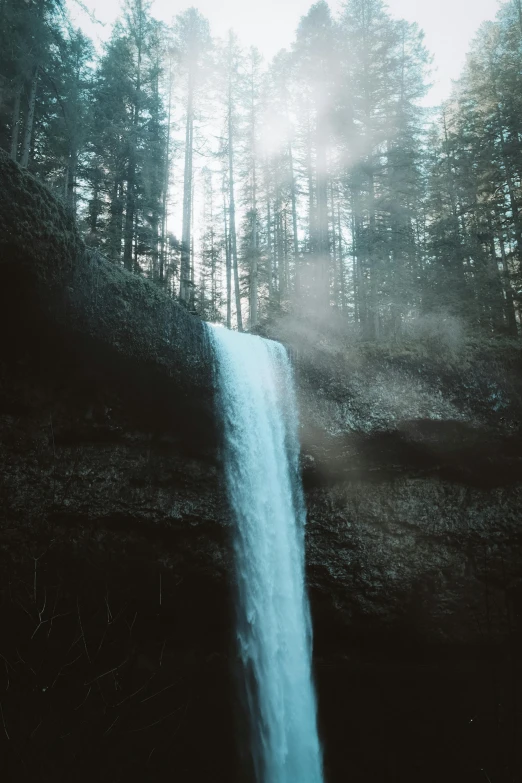 a large waterfall is coming out of the forest