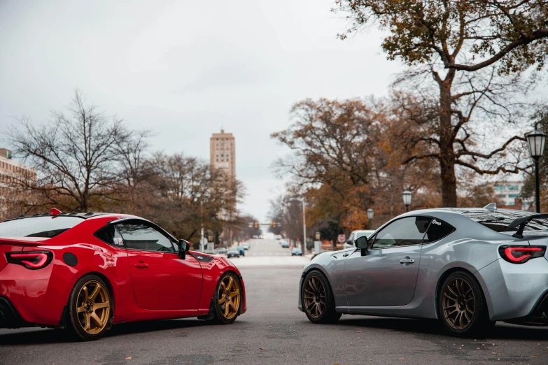 two cars parked on a street in front of some trees