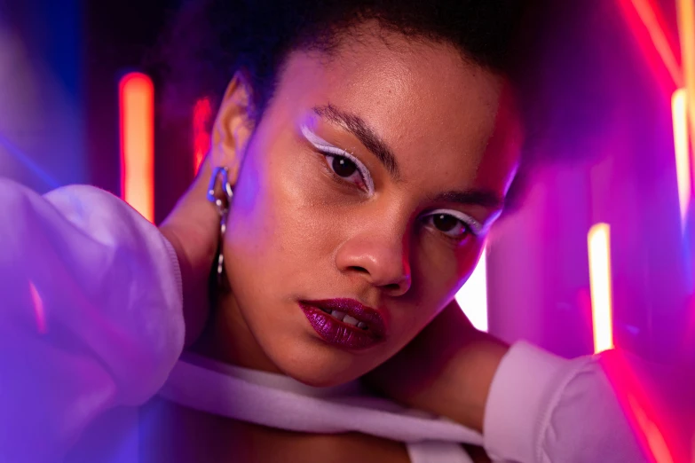 a woman wearing a white top posing in front of neon lights