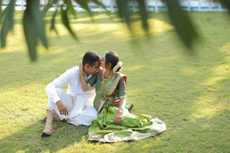 a couple are sitting on grass during a po shoot