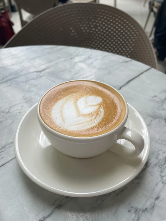 a cappuccino on a saucer at a cafe table