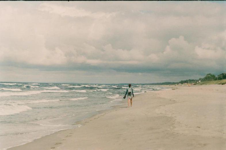 the person is walking on the shore line with surfboards